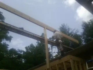 Carpenter setting a ridge beam over a new addition frame — Ice Dam Removal by Roofing Brothers in Thompson